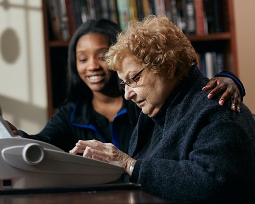 woman typing with smiling caregiver